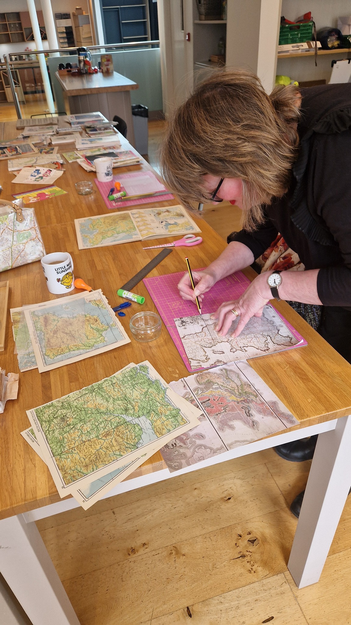 Lady is carefully cutting out paper on a craft mat